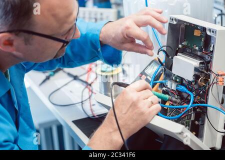Electronics engineer man troubleshooting defects in a hardware product on his test bench Stock Photo