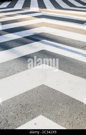White converging lines on a black asphalt background in an unusual crosswalk. Stock Photo