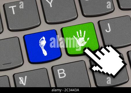 Printout of hand and foot on computer keys Stock Photo