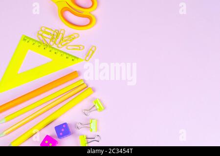 Multi-colored red yellow pinc pencils rulers, pens, pencils and scissors and stationery stand on a pink background. Stock Photo