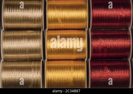 Cutout texture closeup on coils of colored sewing threads gold, yellow and red. Stock Photo
