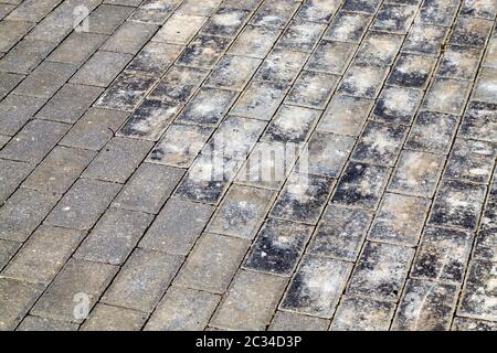 old road made of paving stones for traffic and pedestrians, close-up of a part of the public road , part of the concrete tile is destroyed Stock Photo