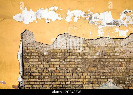 the old brick wall of the house from which part of the plaster has fallen off and destroyed, close-up of an old building during the period of its dest Stock Photo