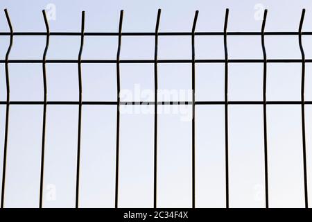 thin metal lattice decorative fence private area, but helps to protect the territory, against the blue sky Stock Photo