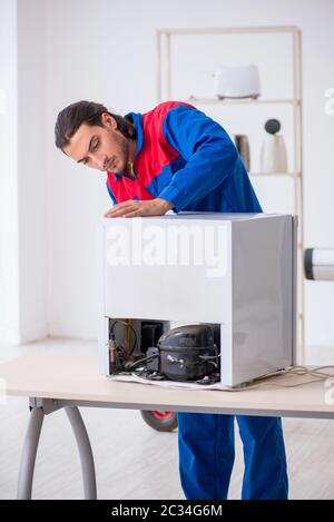Young male contractor repairing refrigerator at workshop Stock Photo