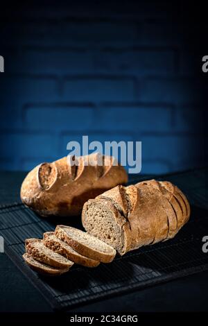 Gluten free multi dark bread on a black table and blue bricks background Stock Photo