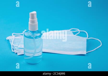 Bottle of hand sanitizer, antimicrobial liquid spray, germ prevention or antibacterial hygiene. Medical mask, Medical protective masks on blue backgro Stock Photo