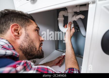 Male Plumber In Overall Fixing Sink Pipe Stock Photo