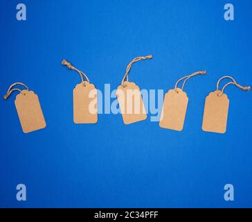 set of empty paper brown rectangular tags on a rope, price tags are on a blue trend background, top view Stock Photo