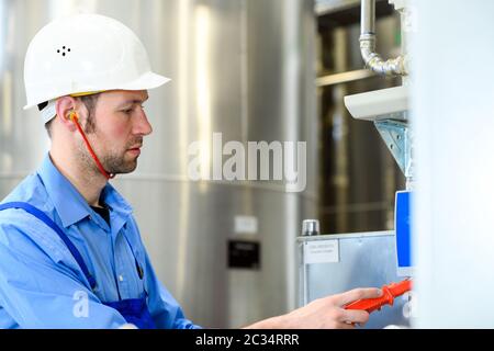 worker with helmet and electric tool  in industrial plant Stock Photo