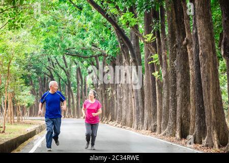 happy asian Senior couple running outside at park Stock Photo
