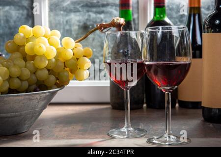Composition with two wineglasses, grapes and bottles of a red wine Stock Photo