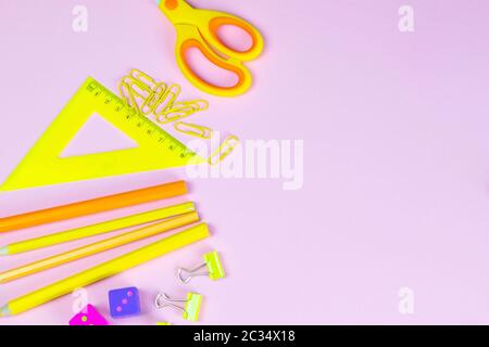 Multi-colored red yellow pinc pencils rulers, pens, pencils and scissors and stationery stand on a pink background. Stock Photo