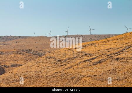 Wind turbines at a wind farm on a mountain in the Israeli Golan Heights. Dry summer day time. Long view with copy space. Stock Photo