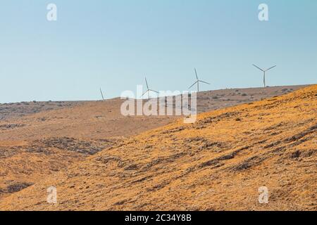 Wind turbines at a wind farm on a mountain in the Israeli Golan Heights. Dry summer day time. Long view with copy space. Stock Photo
