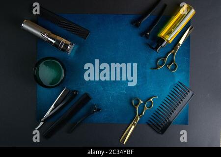 Scissors, hair clipper, combs, dangerous razor, gel for haircuts on a blue sheet on black background. Hairdressing concept. Stock Photo
