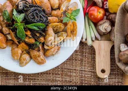 Seafood pasta with clams Black Spaghetti Vongole on white plate on wood table background Stock Photo