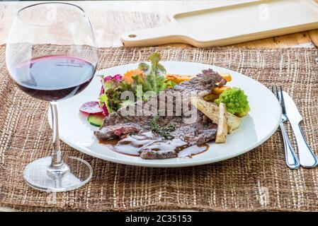Gourmet grilled steak flavoured with basil beef steak with roasted pumpkin and fresh green herb salad Stock Photo