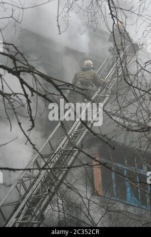 Smoldering remains of a ghetto house with a fireman spraying water Stock Photo