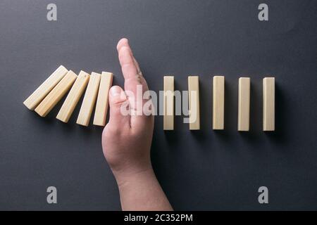 Top view man hand stopping falling dominos in a business crisis management conceptual image. Stock Photo