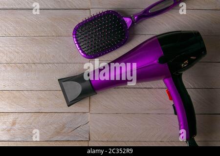Professional hairdresser's set on white woodeb table, top view. Hairdryer, hair and combs. Stock Photo
