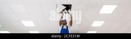 Young Male Electrician On Stepladder Installing Light On Ceiling Stock Photo