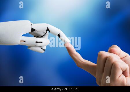 Close-up Of Businessperson Finger Touching Robotic Finger Over White Background Stock Photo