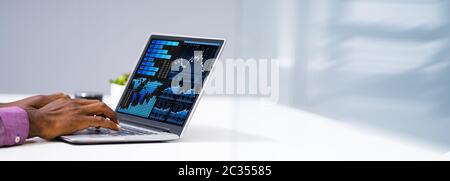 Close-up Of A Businessman's Hand Analyzing Graph On Computer At Workplace Stock Photo