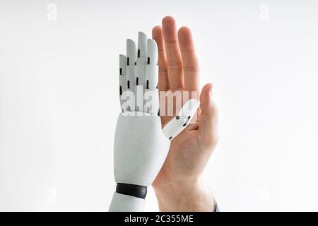 Close-up Of Robot And Man Giving High Five Against Gray Background Stock Photo