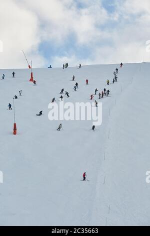 Skiing slope with many unrecognizable skiers coming down Stock Photo