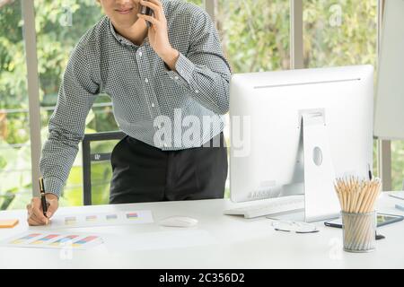 A young Asian businessman is checking the financial documents in his office. Stock Photo