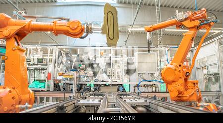 orange robot arms on the production line. controlled by a computer with artificial intelligence. Stock Photo