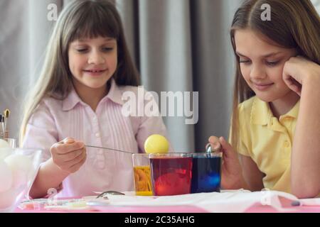 Children paint Easter eggs in glasses with liquid dye Stock Photo