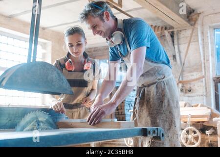 Team of diligent carpenters working on the circular saw Stock Photo