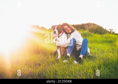 Attractive smiling woman hugging her nice dog. American Stranfrod Stock Photo