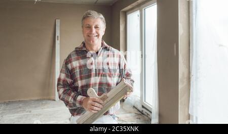Friendly plasterer man in the interior of newly constructed house Stock Photo