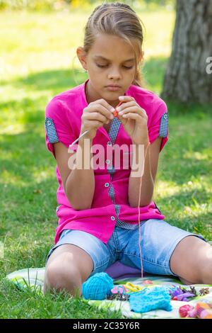 Girl knits on a knitting needles on a picnic in nature Stock Photo