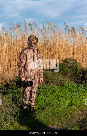 Naturalist photographer in action, with camouflage and camera, in the wilderness. Stock Photo