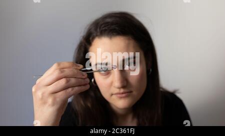 Young woman holding a precious stone with jewelry tweezers. Portrait of a gemologist. Stock Photo