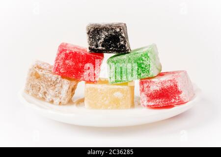 Different colorful Turkish delight cubes are on plate on white background. Stock Photo