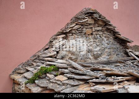 Ruined stone house against pink wall Stock Photo