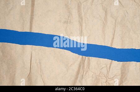 torn brown sheet of paper on a blue background, full frame, close up Stock Photo