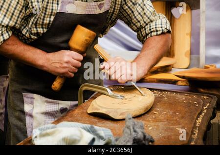 male craftsman working on a carved chopping board, making decorations with a chisel Stock Photo