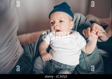 Close up portrait of unrecognizable parents holding their baby. Young happy family, mom and dad playing with cute emotional little newborn child son