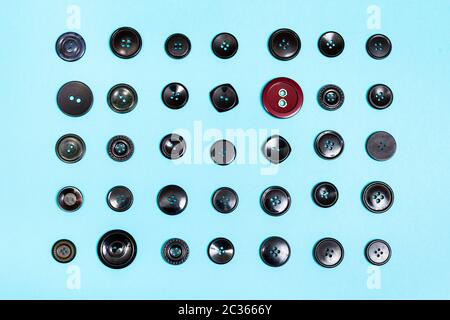 top view of red button between many black buttons on blue background Stock Photo