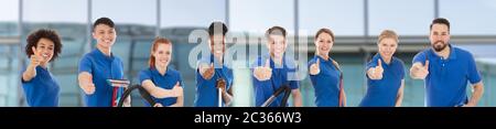 Portrait Of A Smiling Diverse Young Janitors With Cleaning Equipment Against Window Glass Stock Photo