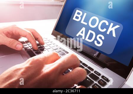 Close-up Of A Businessperson Using Laptop With Block Ads Message On Screen At Office Stock Photo