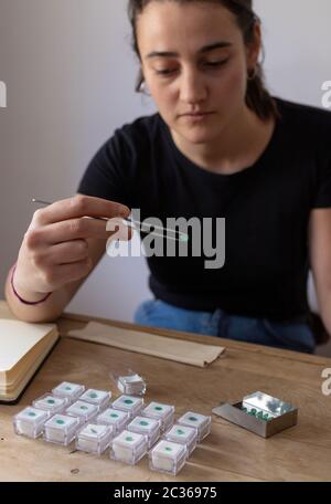 Young woman holding a precious stone with jewelry tweezers. Portrait of a gemologist. Stock Photo