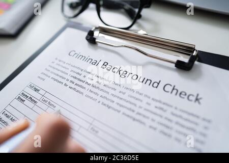 Close-up Of Human Hand Filling Criminal Background Check Application Form With Pen Stock Photo