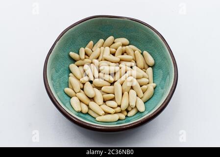 Pine nuts in ceramic bowl, isolated on white background Stock Photo